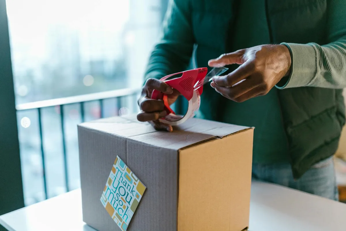 Ecommerce seller measuring a DHL parcel with a tape measure and weighing it on a digital scale in a Malaysian home office
