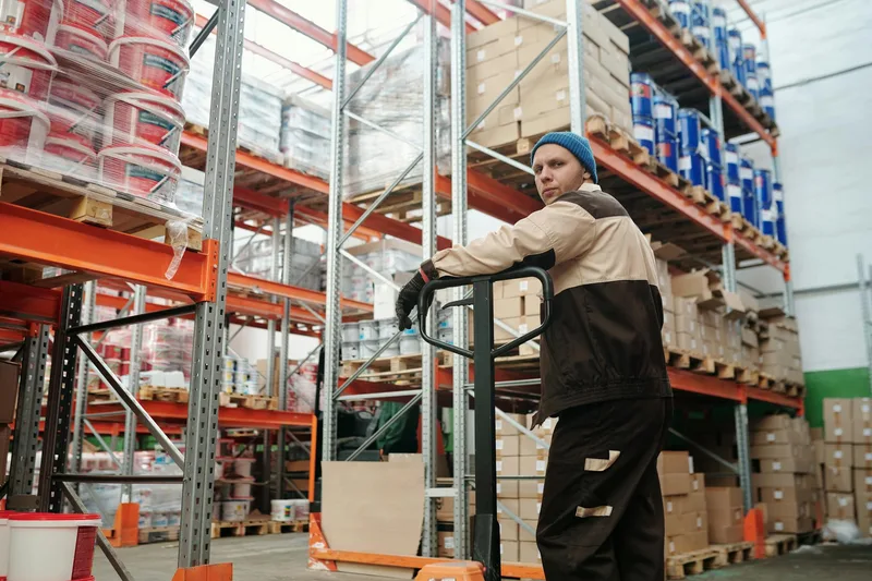 A fulfillment station showing a worker selecting between different sized cardboard boxes for order packing
