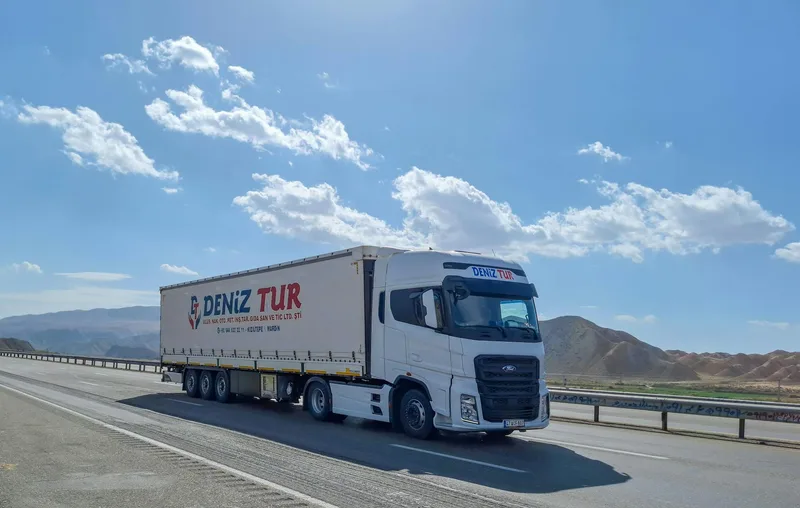Cross-border shipping truck on UAE-Saudi Arabia highway with logistics parcel tracking illustration